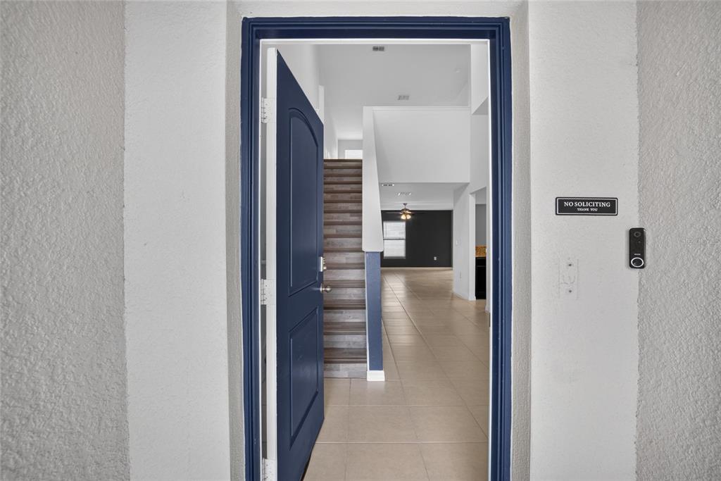 An open dark blue front door reveals a tiled entryway leading to a staircase — 1115 WYNNMERE WALK AVENUE, RUSKIN, FL