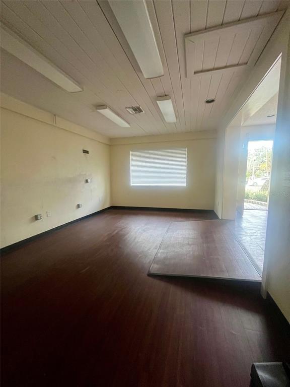 An interior view of an empty room with wood-look flooring, a window, and ceiling lights — 130 E 1ST STREET, APOPKA, FL