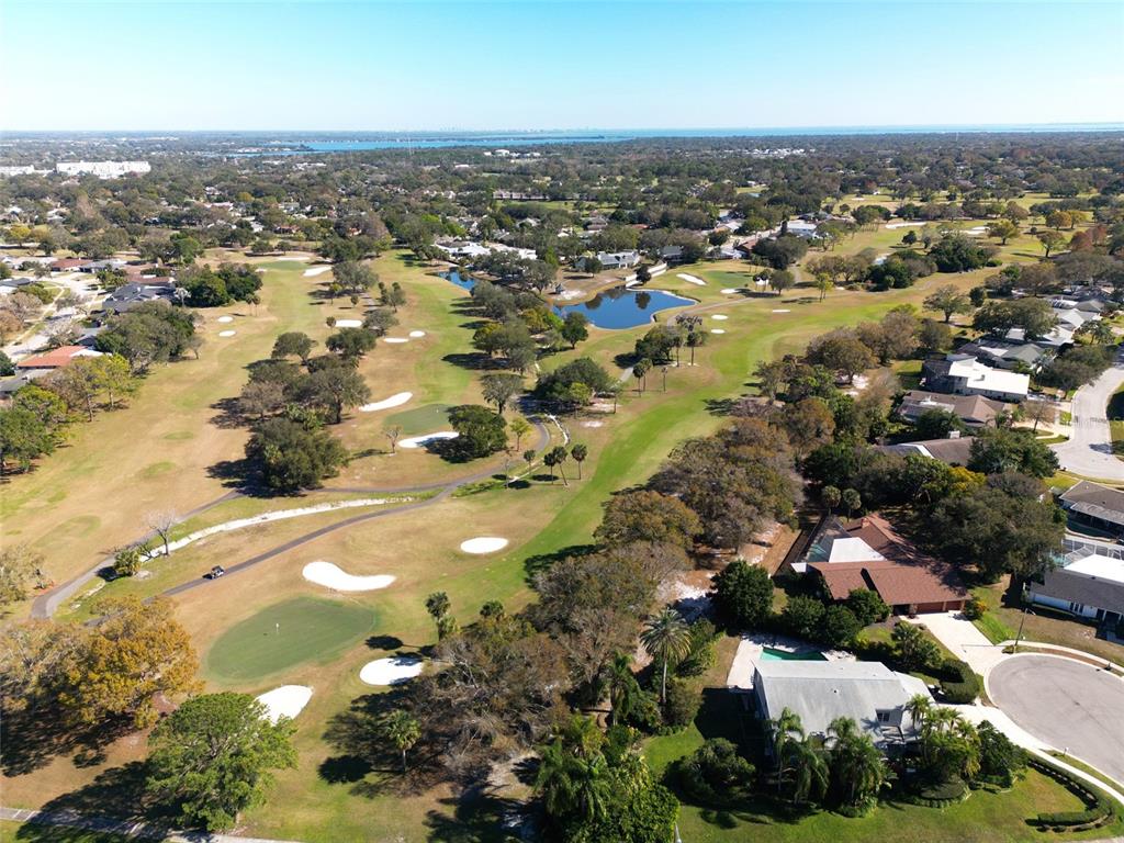 An aerial view shows a golf course with sand traps, a pond, and surrounding houses — 2668 CONCORDE COURT, CLEARWATER, FL