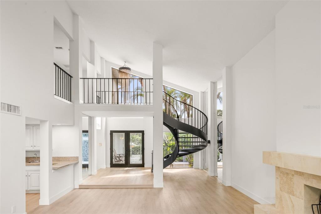 A bright living area features light wood floors, a spiral staircase, and a second-floor balcony — 2668 CONCORDE COURT, CLEARWATER, FL