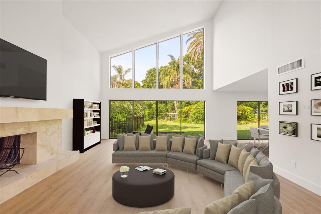 A spacious living room features a large sectional sofa, fireplace, and floor-to-ceiling windows — 2668 CONCORDE COURT, CLEARWATER, FL