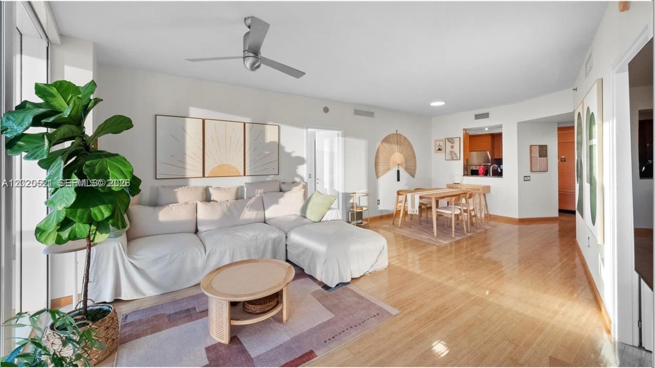 A living and dining area features light wood flooring, a sectional sofa, and a ceiling fan — 450 Alton Rd # 2810, Miami Beach FL 33139, MIAMI BEACH, FL