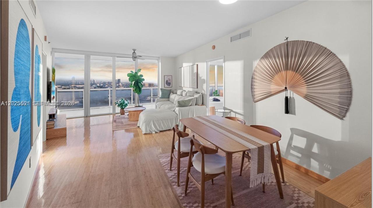 A bright living and dining area features wood floors, a large wall fan, and floor-to-ceiling windows — 450 Alton Rd # 2810, Miami Beach FL 33139, MIAMI BEACH, FL