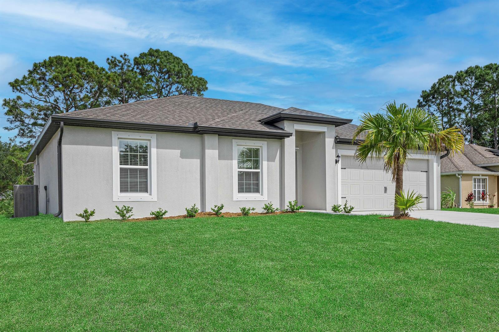A single-story house with a light-colored stucco exterior, a two-car garage, and a lawn — 9350 104th Court, Vero Beach FL 32967, VERO BEACH, FL
