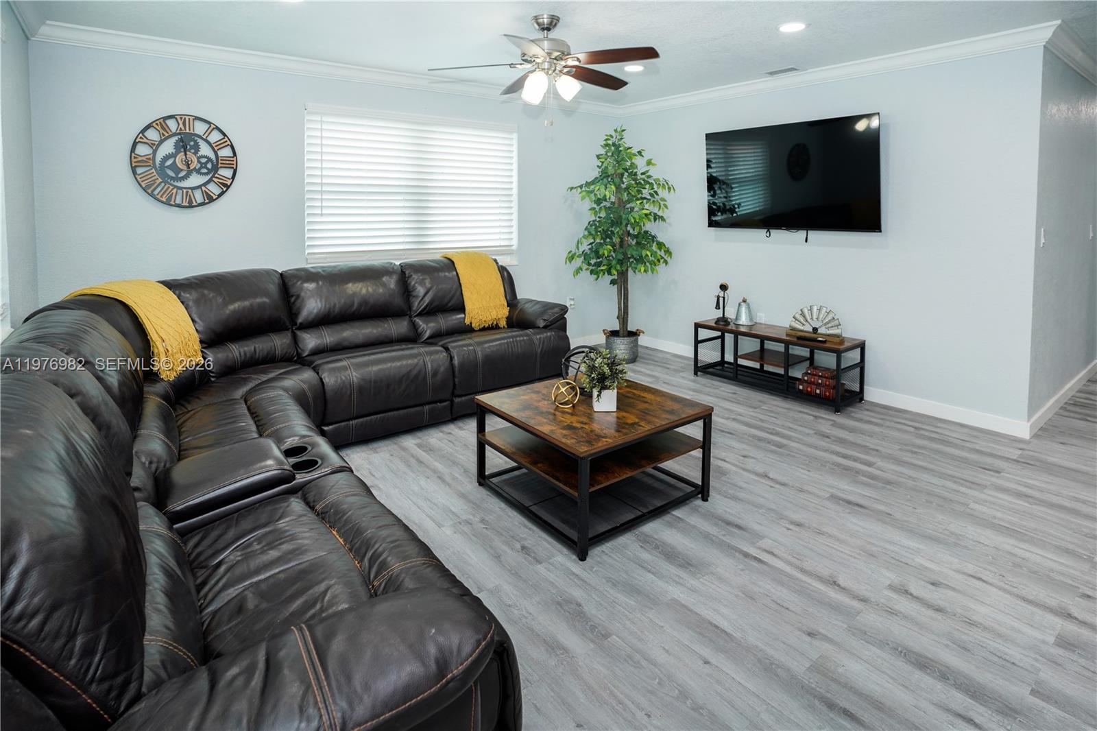 A living room features a dark leather sectional, a wood coffee table, and a wall-mounted television — 1647 NW 29th Ave, Miami FL 33125, MIAMI, FL