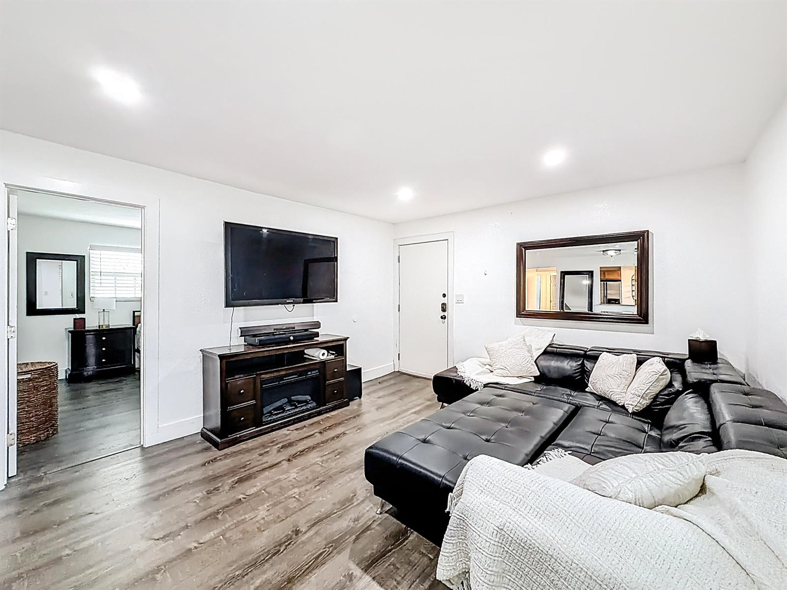 A living room features a black sectional sofa, a television on a media console, and flooring — 305 SE 11th Avenue # D, Pompano Beach FL 33060, POMPANO BEACH, FL