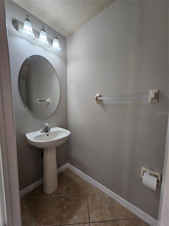 A small bathroom features a pedestal sink, an oval mirror, and a towel bar — 2954 WILLOWLEAF LANE, WESLEY CHAPEL, FL