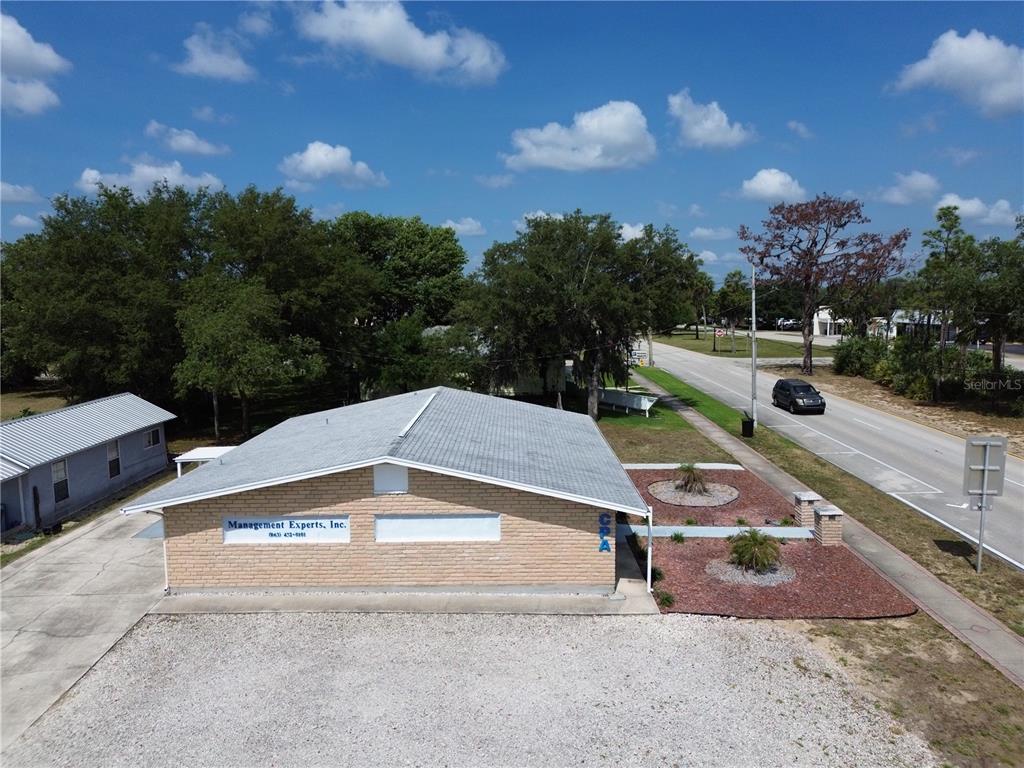 An aerial view shows a single-story brick commercial building with a gravel parking lot — 601 W MAIN STREET, AVON PARK, FL
