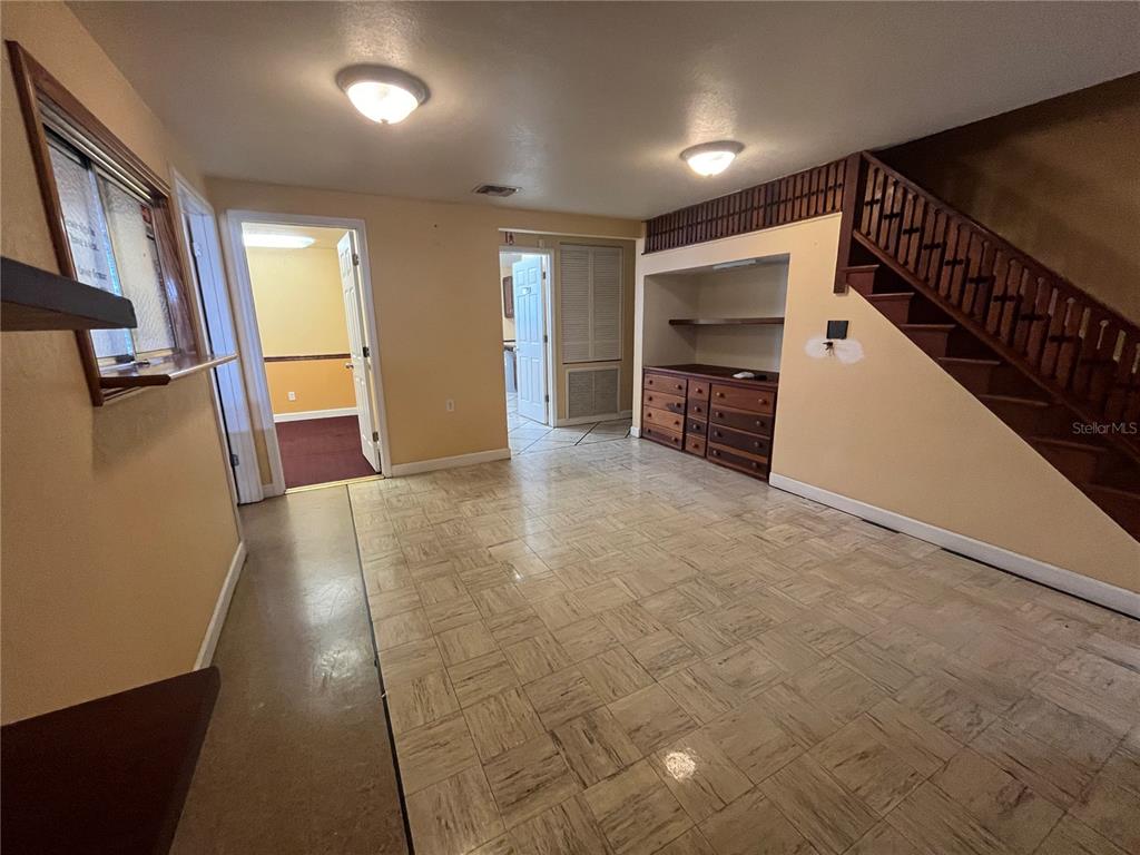 A room with tile flooring, a wooden staircase, and built-in shelving under the stairs — 601 W MAIN STREET, AVON PARK, FL