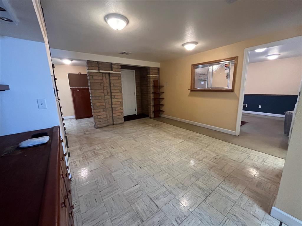 A room with light-colored tile flooring, a brick accent wall, and a doorway leading elsewhere — 601 W MAIN STREET, AVON PARK, FL