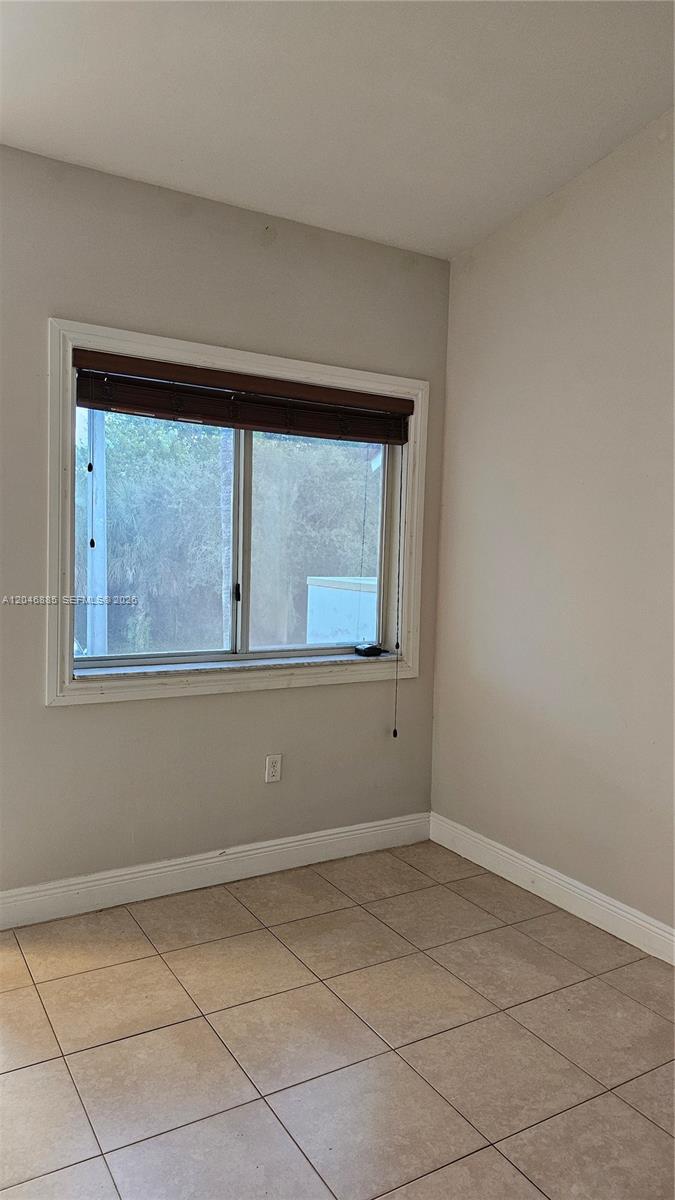 A room with beige walls, light-colored tile flooring, and a window with a brown shade — DAVIE, FL