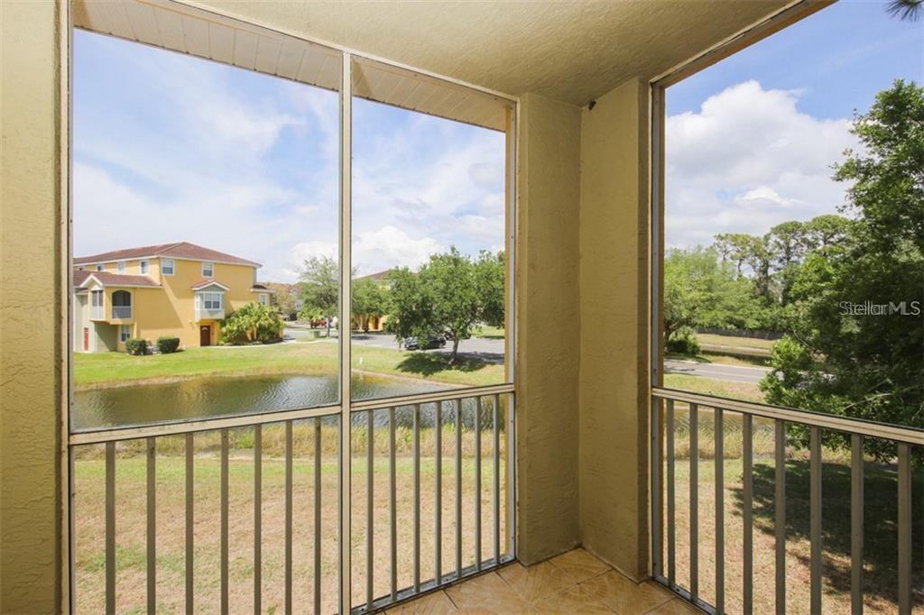 A screened-in balcony overlooks a small pond and a neighboring apartment building — 5655 BENTGRASS DRIVE UNIT 9-117, SARASOTA, FL