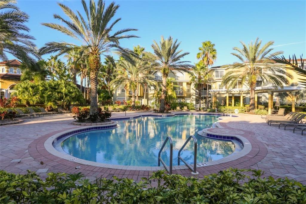 A swimming pool surrounded by a brick deck, palm trees, and multi-story apartment buildings — 5655 BENTGRASS DRIVE UNIT 9-117, SARASOTA, FL