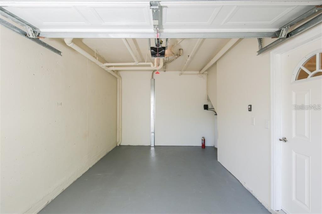 An empty garage with white walls, a gray floor, and exposed ceiling pipes — 5655 BENTGRASS DRIVE UNIT 9-117, SARASOTA, FL