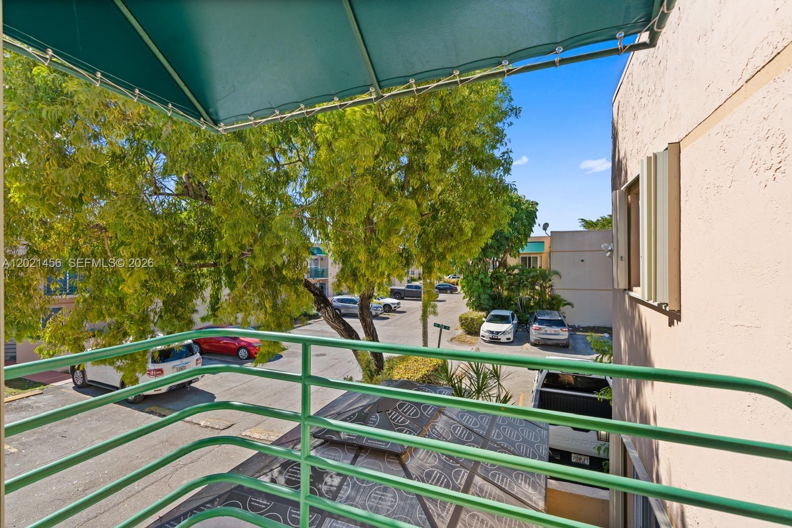 A view from a balcony overlooking a parking lot with several cars and trees — 11860 SW 18th Terr # 103, Miami FL 33175, MIAMI, FL