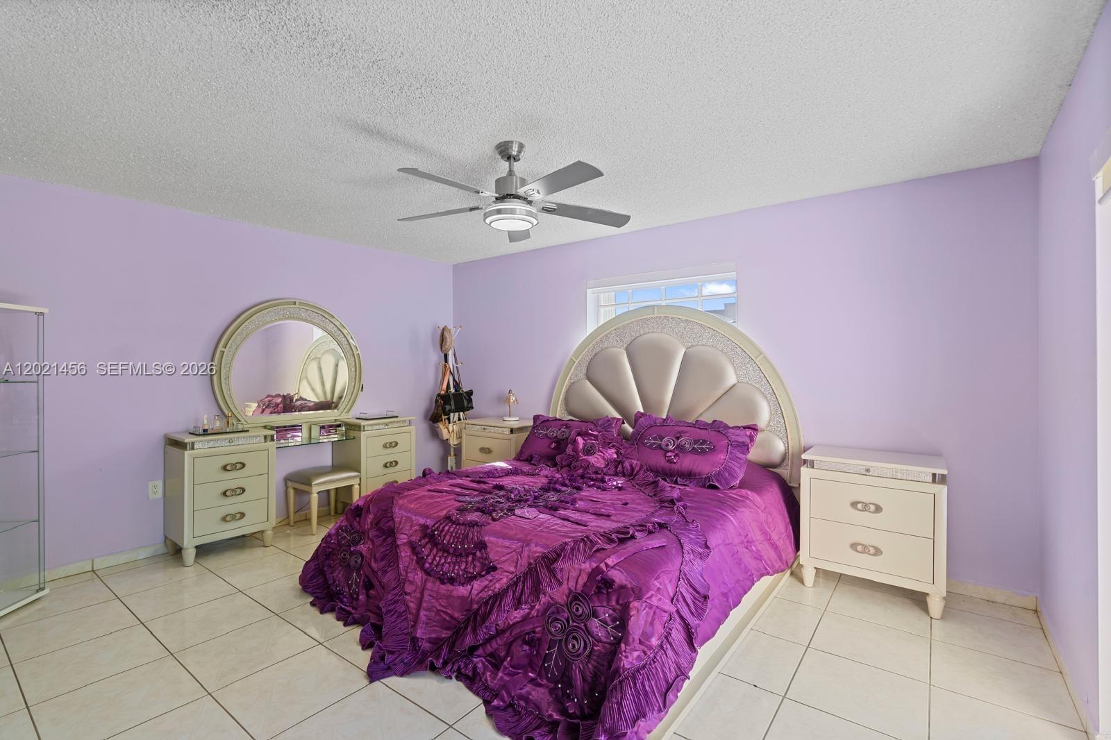 A bedroom features purple walls, tile flooring, a ceiling fan, and a large bed — 11860 SW 18th Terr # 103, Miami FL 33175, MIAMI, FL
