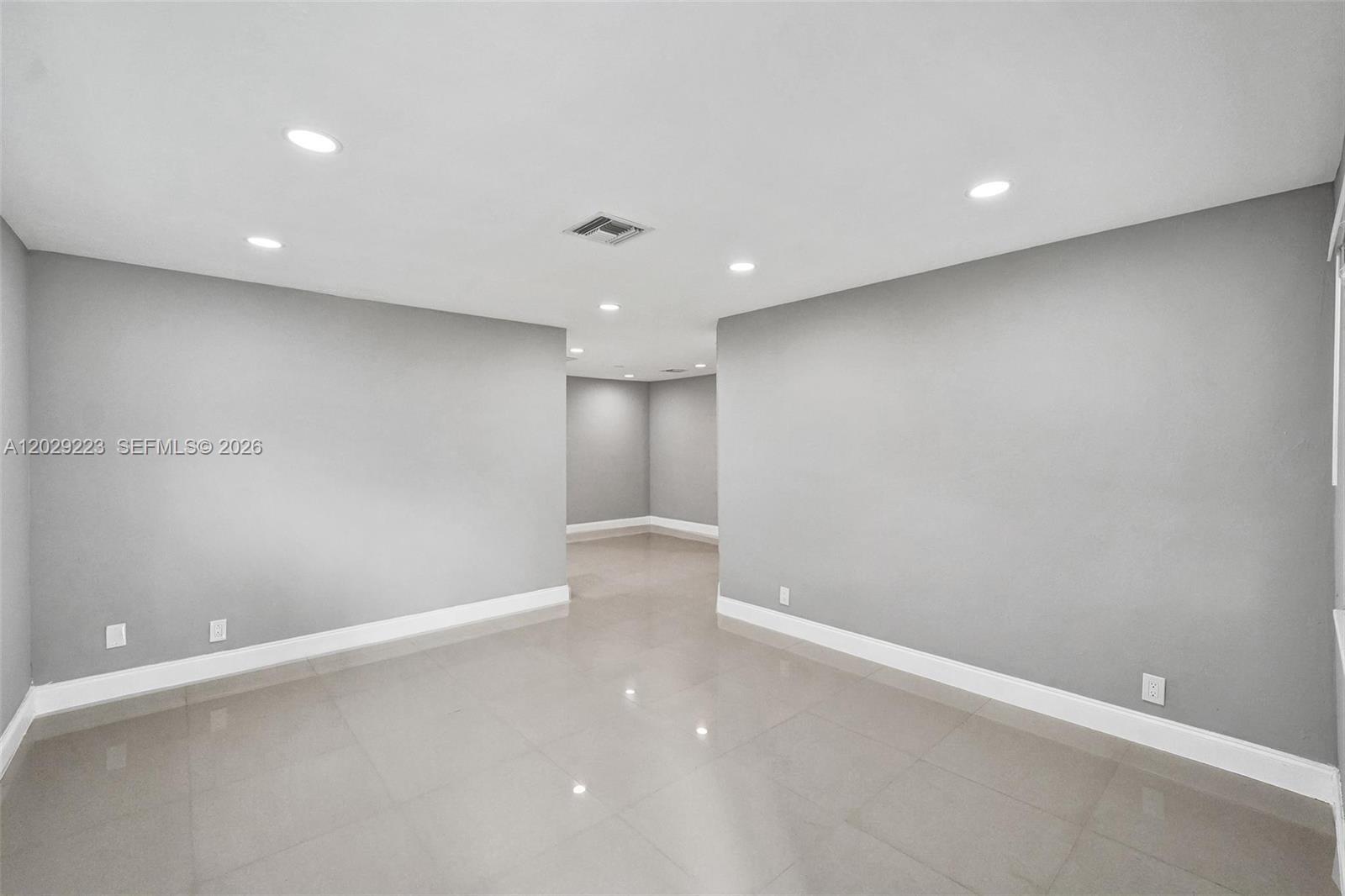 A minimalist room features light gray walls, recessed ceiling lights, and polished tile flooring — 1423 Garfield St, Hollywood FL 33020, HOLLYWOOD, FL