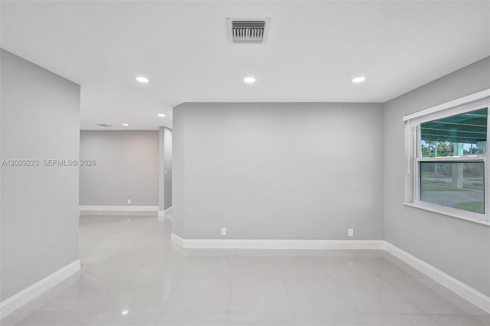 A bright, empty room features light gray walls, white tile flooring, and recessed ceiling lighting — 1423 Garfield St, Hollywood FL 33020, HOLLYWOOD, FL
