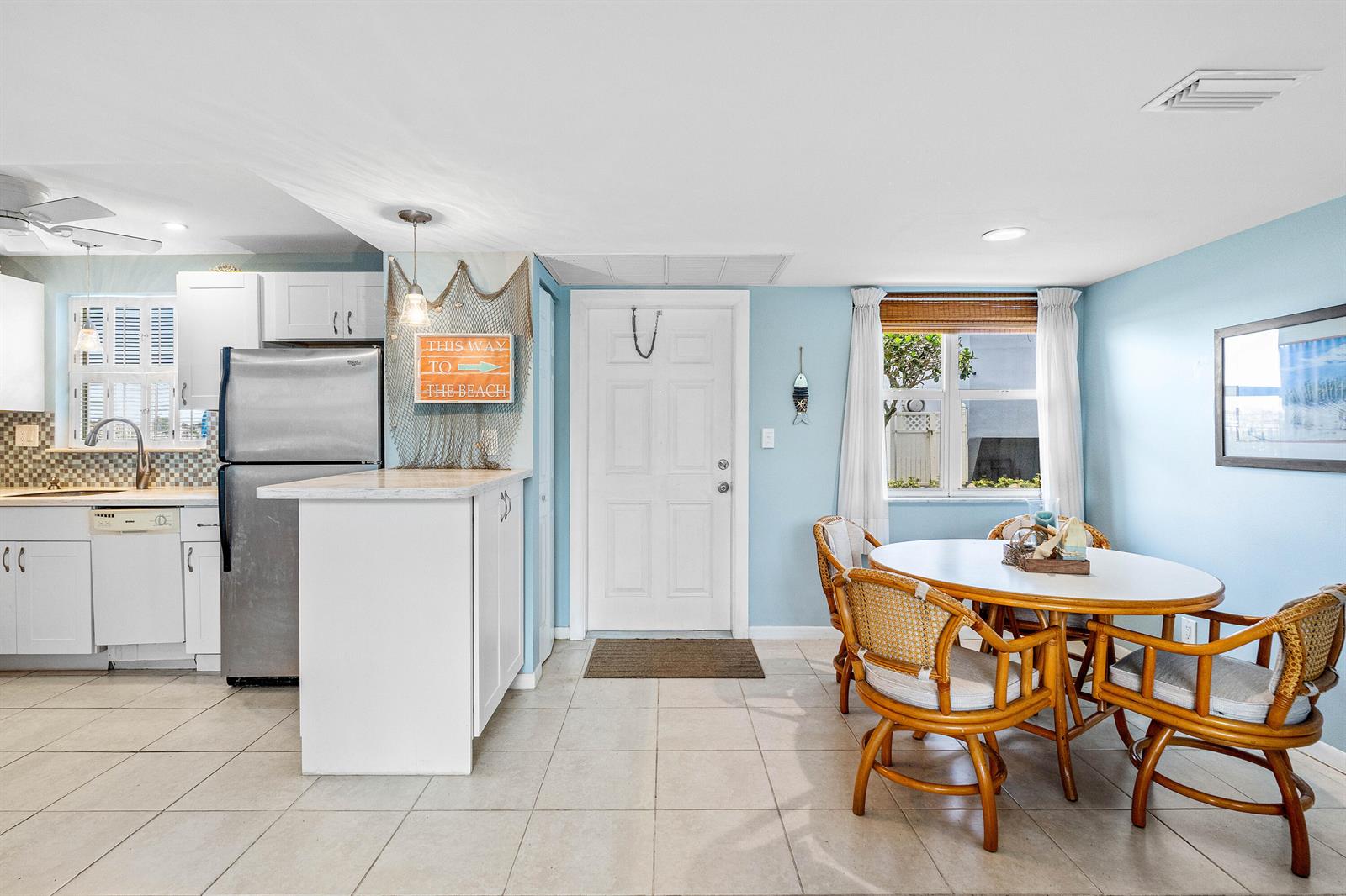 A kitchen and dining area with white cabinets, stainless steel appliances, and rattan chairs — 1820 New Palm Way # 103, Boynton Beach FL 33435, BOYNTON BEACH, FL