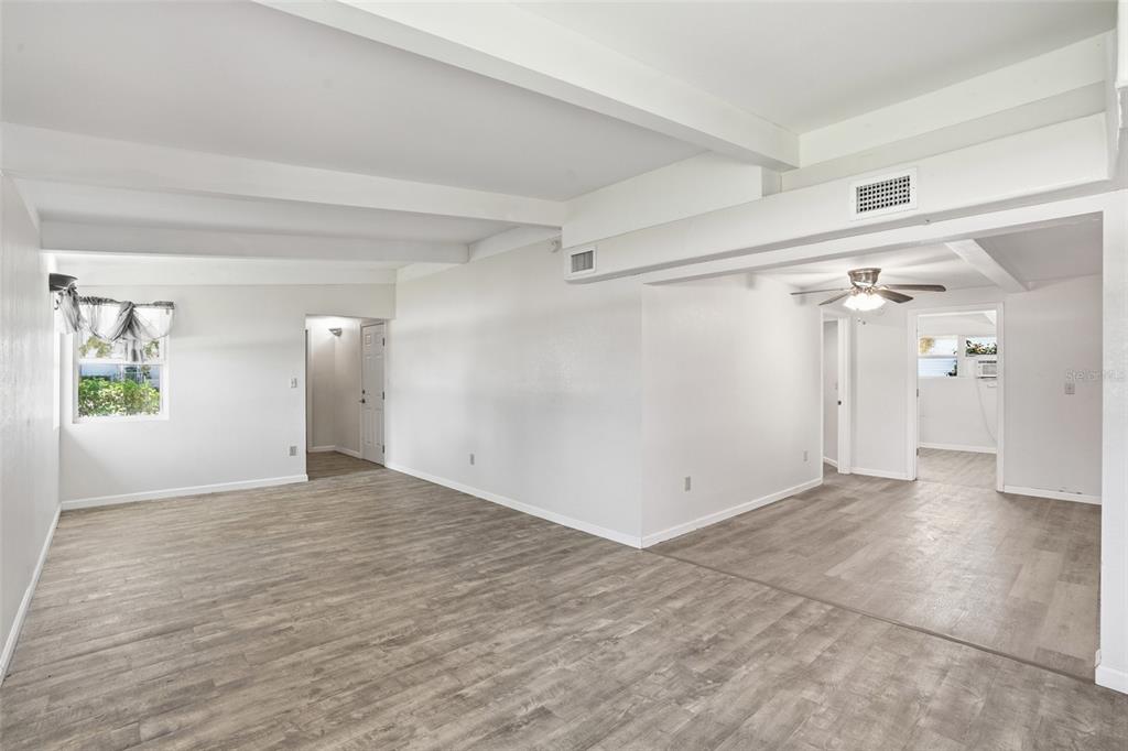 An interior view of a room with white walls, exposed ceiling beams, and wood-look flooring — 503 MYRTLE STREET, PUNTA GORDA, FL