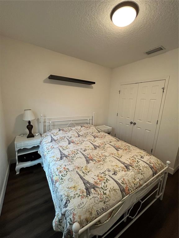 A bedroom features a white metal bed frame, a patterned quilt, and two white nightstands — 9213 HALSEY DR, GROVELAND, FL