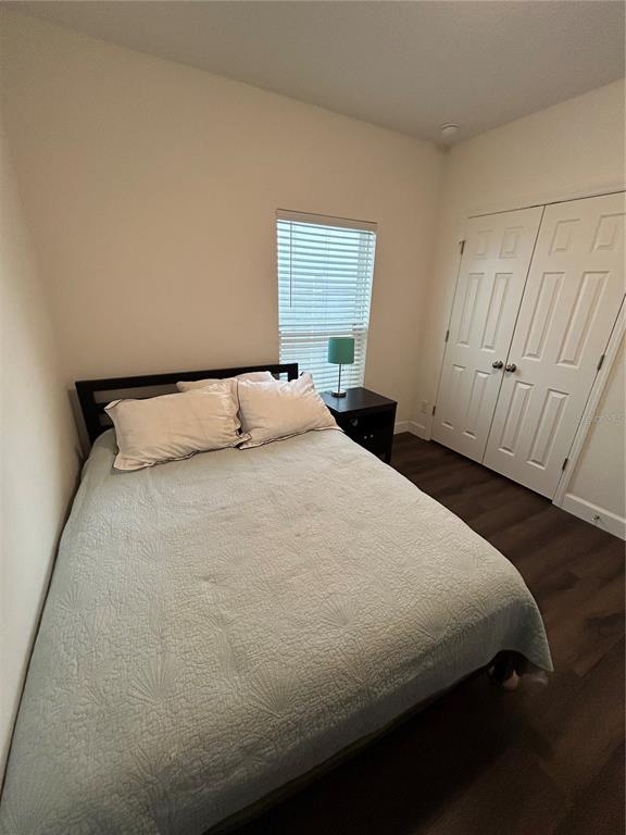 A bedroom features a bed with a light blue quilt, a window, and white closet doors — 9213 HALSEY DR, GROVELAND, FL