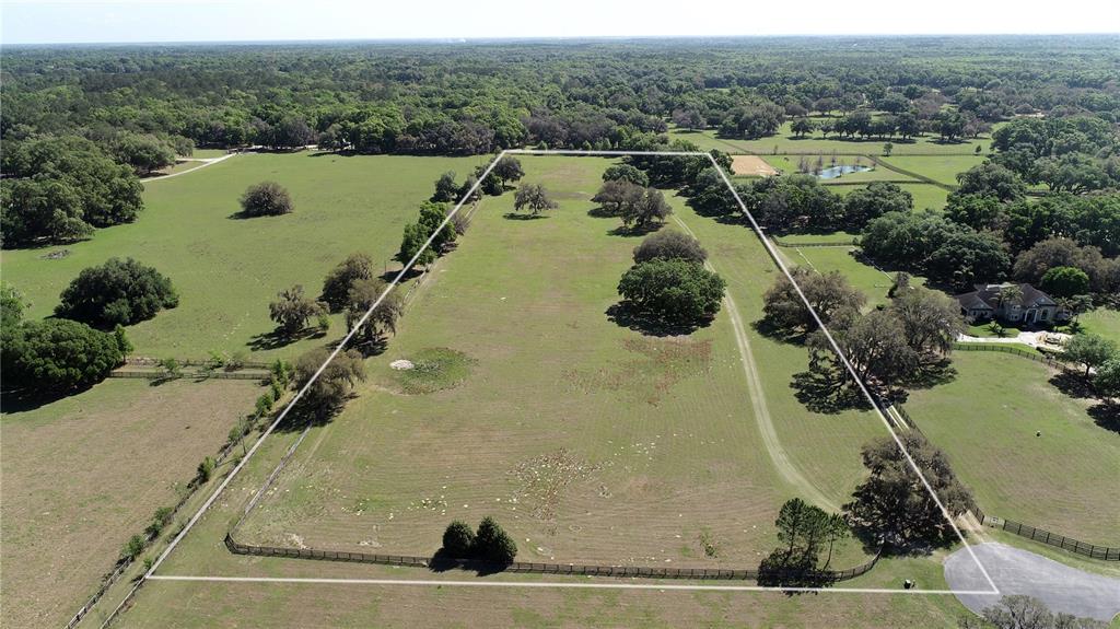 An aerial view shows a large, fenced rectangular pasture with scattered trees and surrounding woods — TBD SW 104TH  ST ROAD, OCALA, FL
