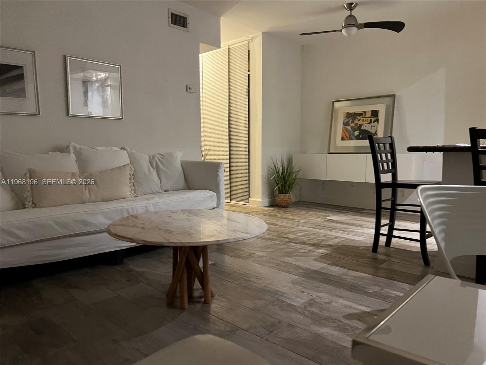 A living room features a white sofa, a marble coffee table, and wood-look tile flooring — 1334 Euclid Ave # 7, Miami Beach FL 33139, MIAMI BEACH, FL