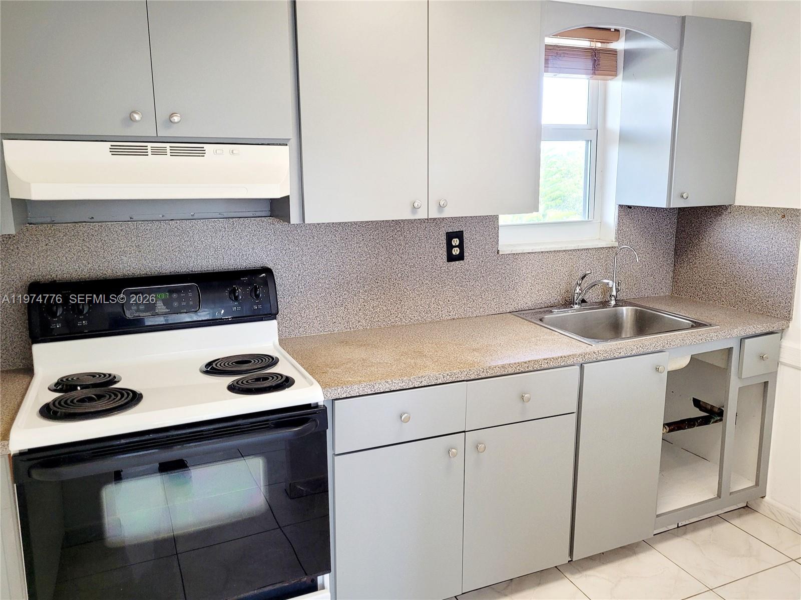 A kitchen features gray cabinets, a white electric stove, a stainless steel sink, and countertops — 1700 NE 191st St # 402, Miami FL 33179, MIAMI, FL