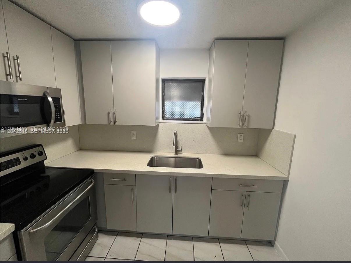 A kitchen features light gray cabinets, stainless steel appliances, and a white countertop — 1717 NW 16th St, Miami FL 33125, MIAMI, FL