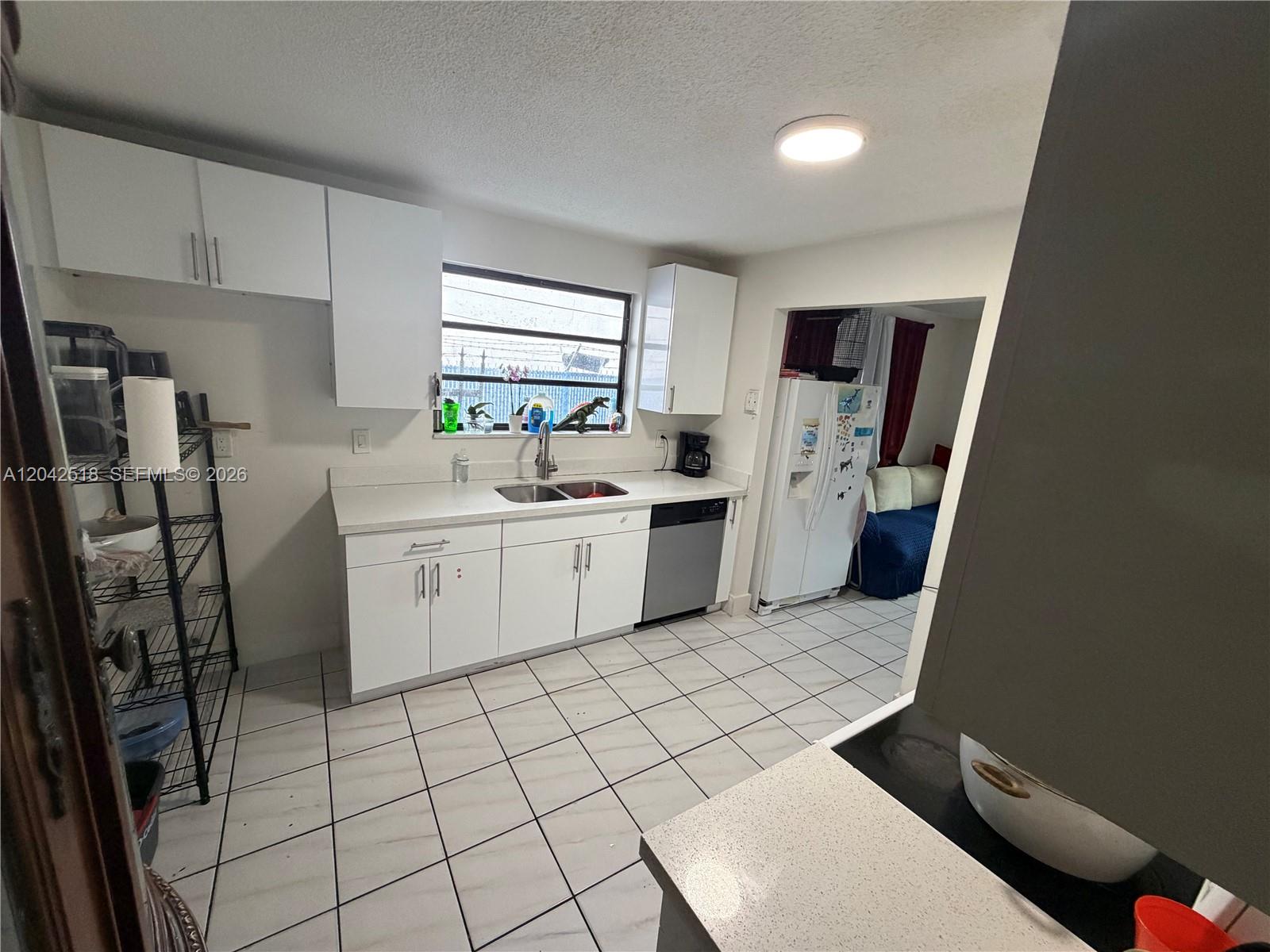 A kitchen features white cabinets, white countertops, a stainless steel dishwasher, and tiled flooring — 1717 NW 16th St, Miami FL 33125, MIAMI, FL