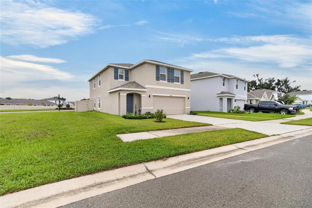 A two-story suburban house with a beige exterior, blue shutters, and an attached garage — 13646 MOUNT IVY COURT, DADE CITY, FL