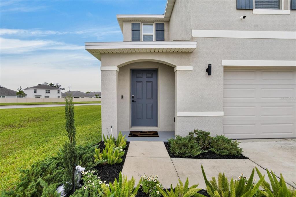 A gray front door with a covered entryway and a concrete walkway leading to it — 13646 MOUNT IVY COURT, DADE CITY, FL