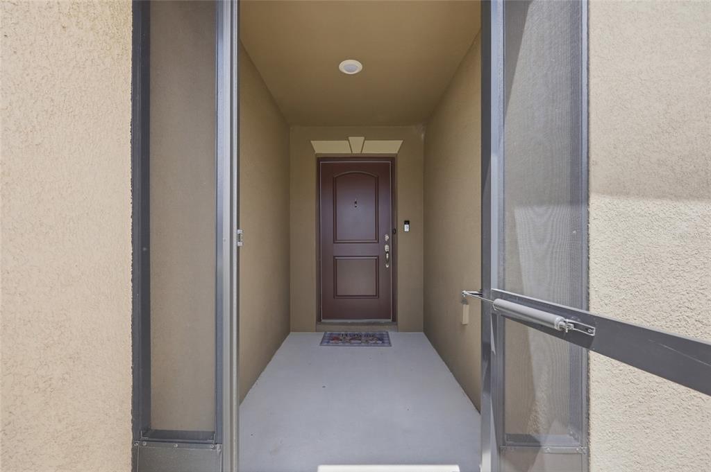 A view through a screen door into a covered entryway with a brown front door — 1607 SWAN LAKE CIRCLE, DUNDEE, FL