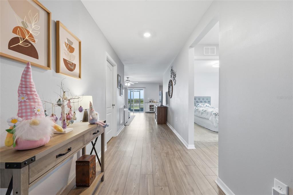 A hallway with wood-look flooring leads to a living area with a view of the outdoors — 1607 SWAN LAKE CIRCLE, DUNDEE, FL