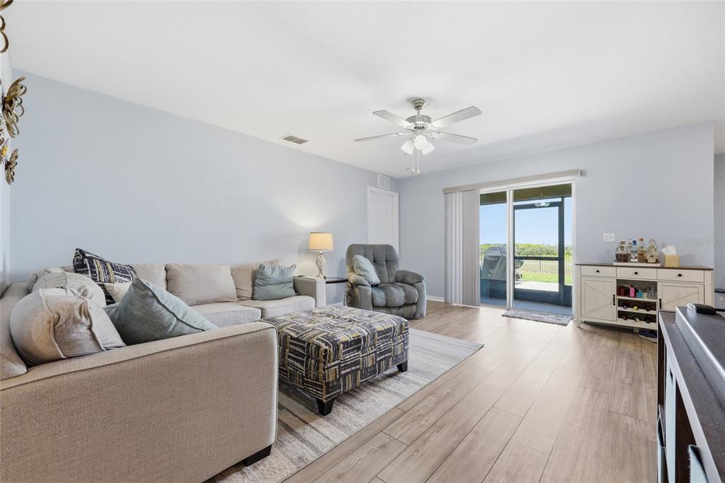 A living room features light-colored walls, wood-look flooring, a sectional sofa, and a sliding glass door — 1607 SWAN LAKE CIRCLE, DUNDEE, FL