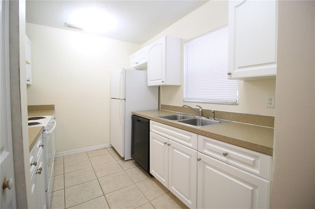 A kitchen with white cabinets, a white refrigerator, a black dishwasher, and tan countertops — 720 NEWTON AVENUE S, ST PETERSBURG, FL