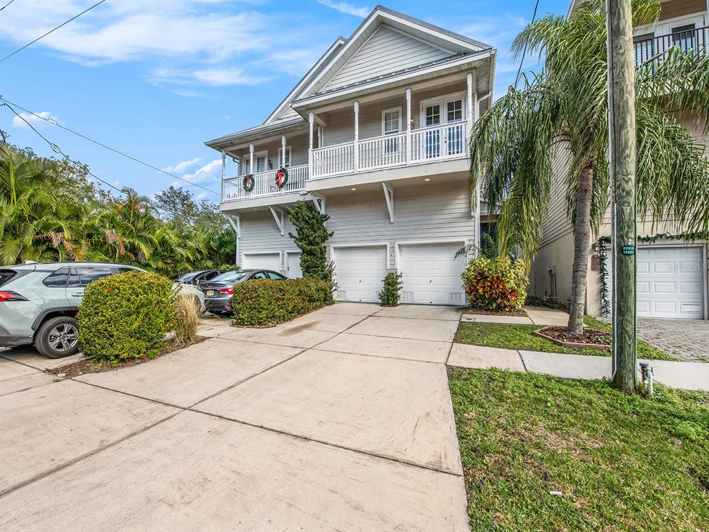 A two-story house with a white exterior, a balcony, and a multi-car garage — 6810 KISSIMMEE STREET S, TAMPA, FL