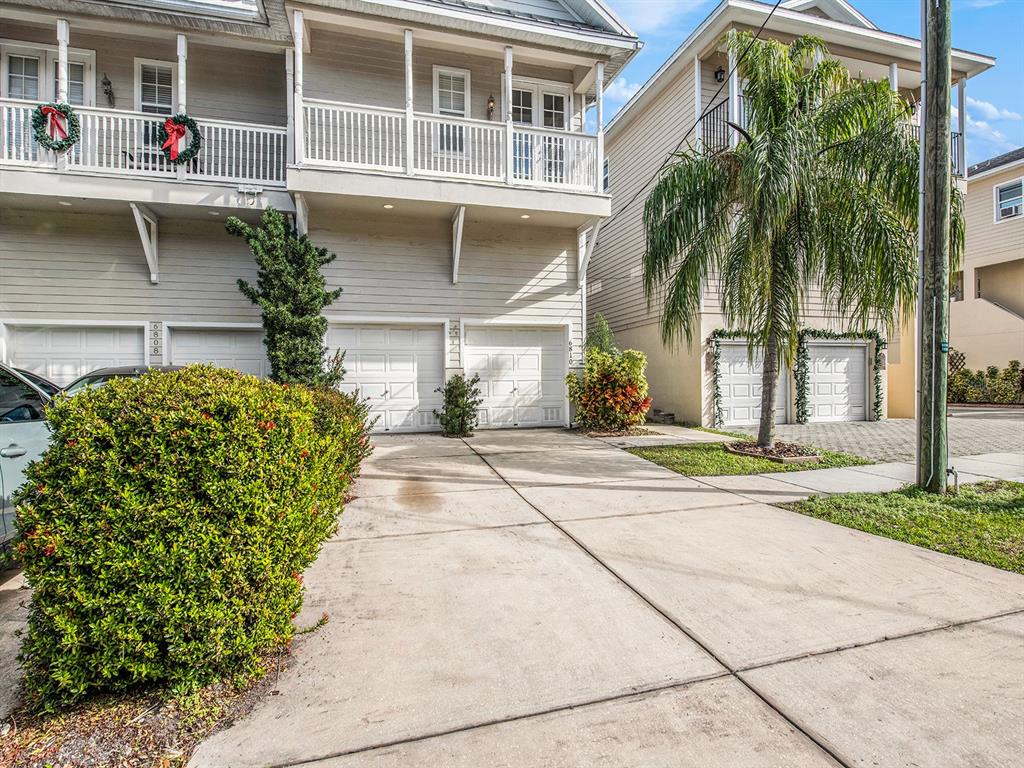A concrete driveway leads to the garages of two multi-story townhomes with white siding — 6810 KISSIMMEE STREET S, TAMPA, FL