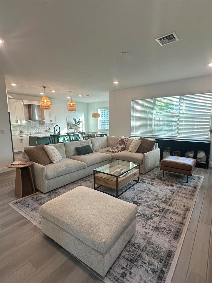 A living room with a large sectional sofa, glass coffee table, and area rug — 1131 Verde Court, Deerfield Beach FL 33064, DEERFIELD BEACH, FL