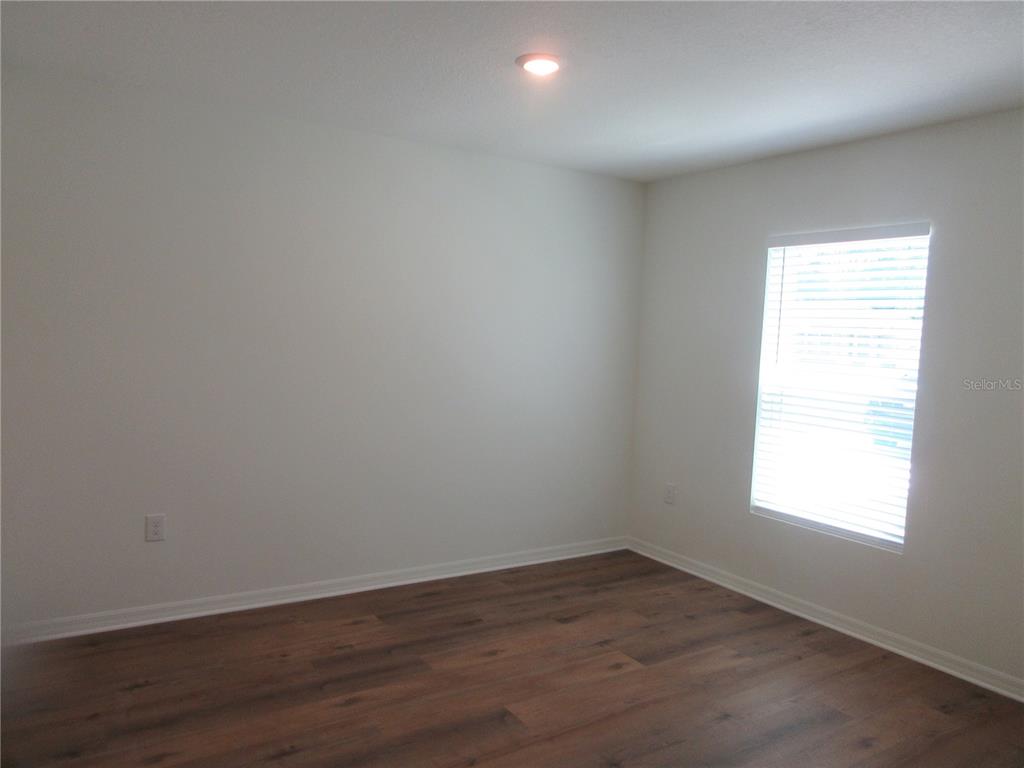 An empty bedroom features white walls, a single window with blinds, and wood-look flooring — 13130 SW 78TH CIRCLE, OCALA, FL