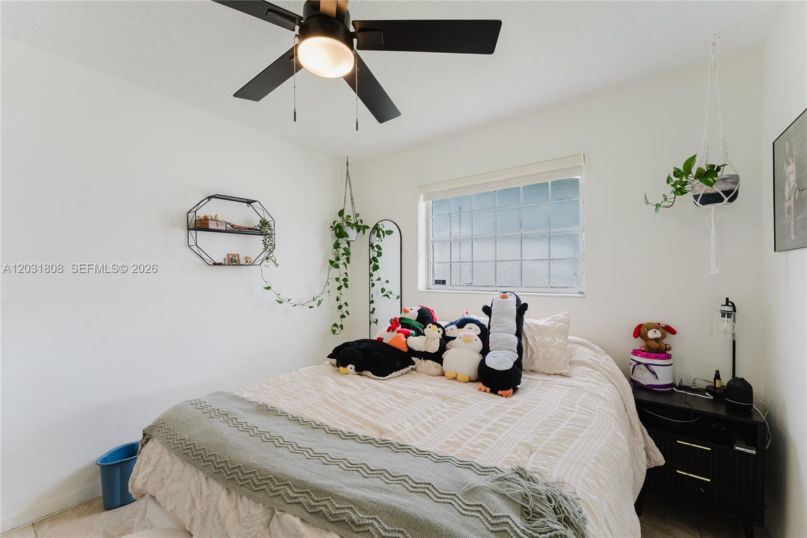 A bedroom features a bed with plush penguin toys, a ceiling fan, and hanging plants — 2604 NW 48th St, Tamarac FL 33309, TAMARAC, FL
