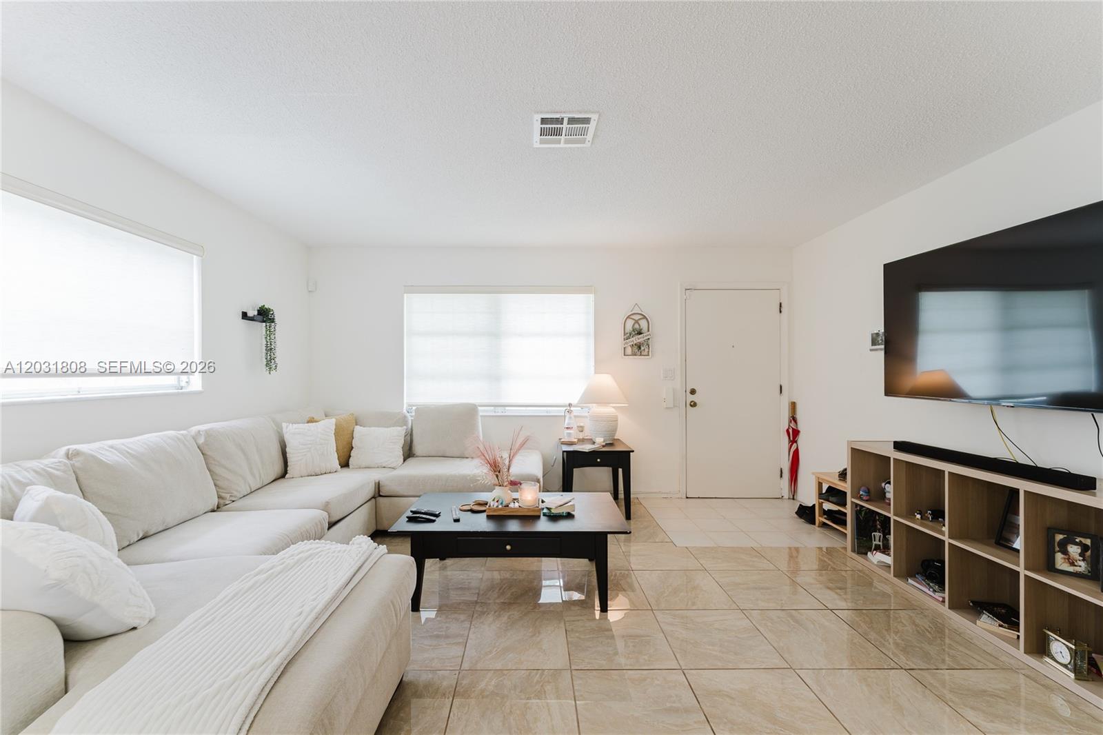 A living room features a large sectional sofa, a coffee table, and a wall-mounted television — 2604 NW 48th St, Tamarac FL 33309, TAMARAC, FL