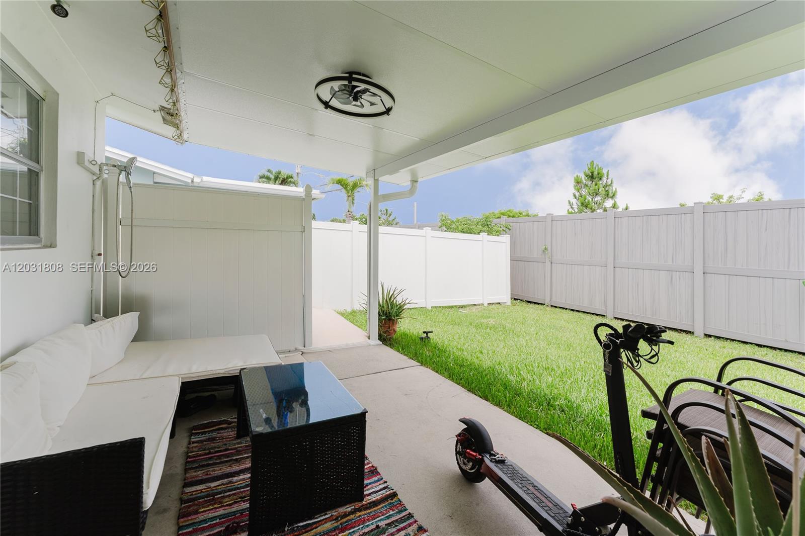 A covered patio features outdoor furniture, a scooter, and a fenced backyard with grass — 2604 NW 48th St, Tamarac FL 33309, TAMARAC, FL