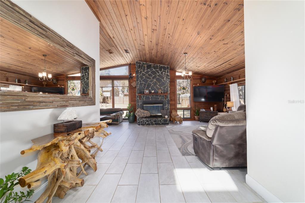 A living room features a stone fireplace, wood-paneled vaulted ceiling, and light-colored tile flooring — 3510 SW 5TH COURT, OCALA, FL
