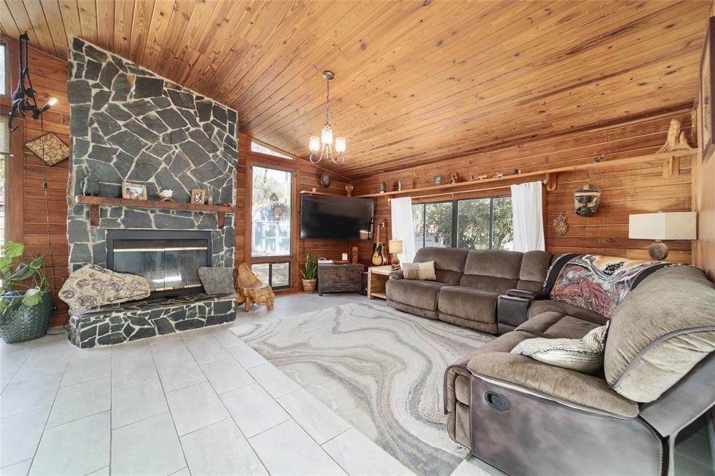 A living room features a stone fireplace, wood-paneled walls, a vaulted ceiling, and a sectional sofa — 3510 SW 5TH COURT, OCALA, FL