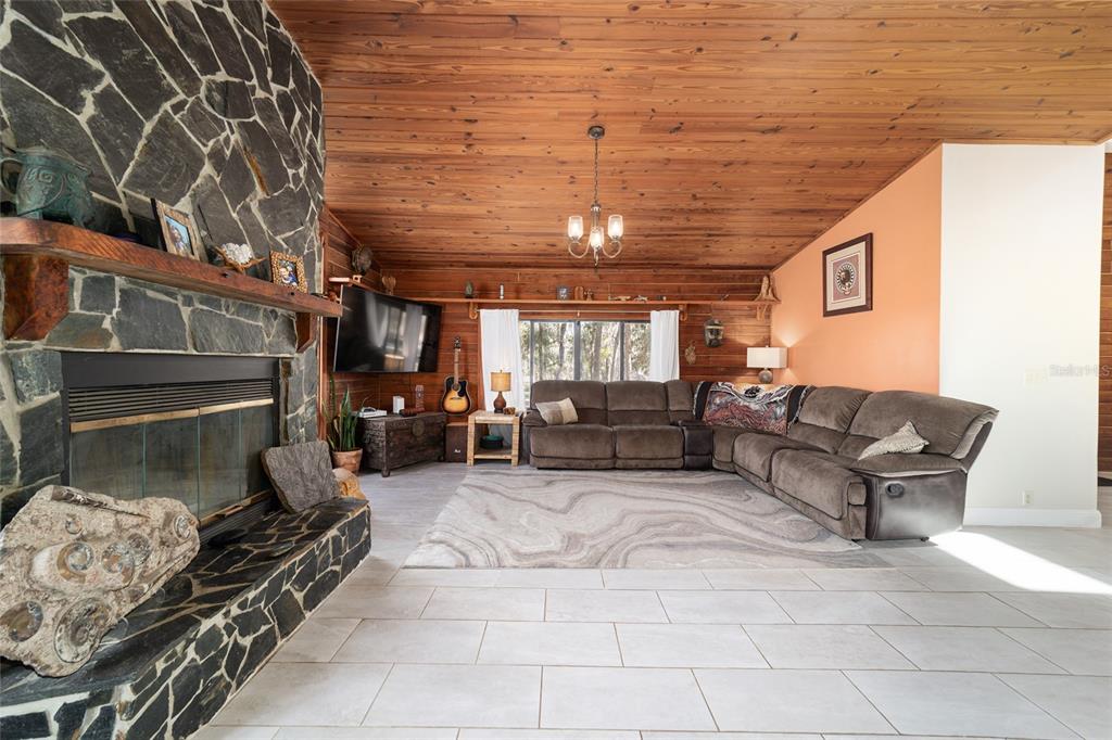 A living room features a stone fireplace, wood-paneled ceiling, and a large sectional sofa — 3510 SW 5TH COURT, OCALA, FL