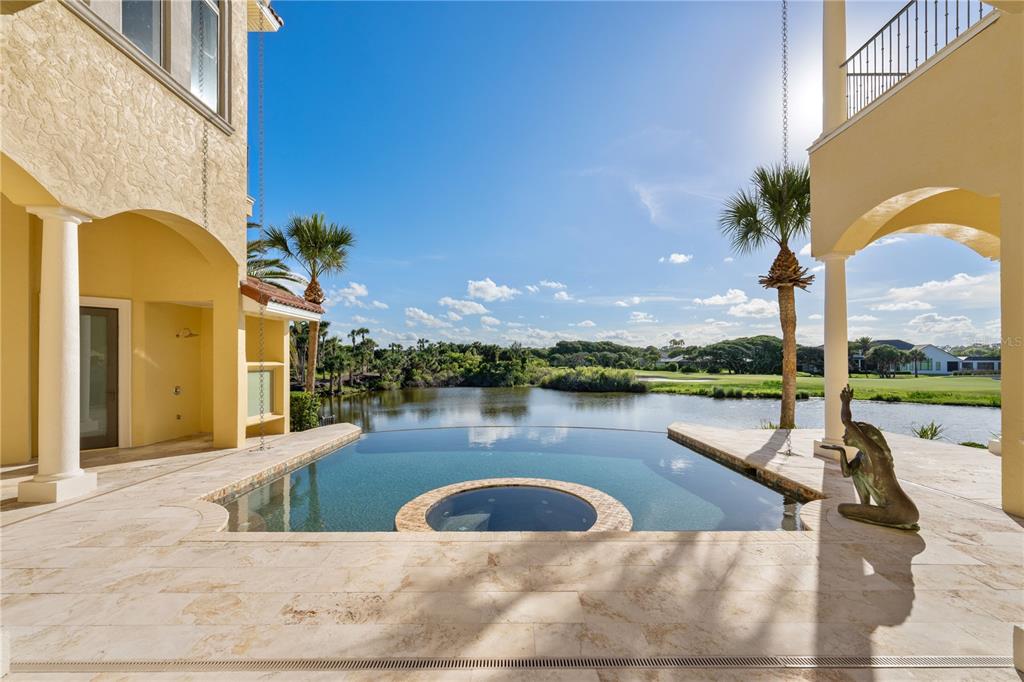 A kitchen island with bar stools faces large windows overlooking a golf course and ocean — 501 GRANADA DRIVE, PALM COAST, FL