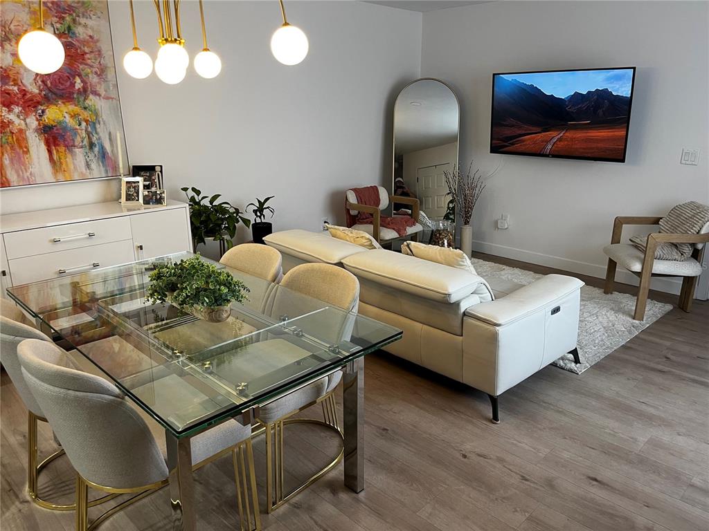 A dining area with a glass table and a living room with a wall-mounted television — 110 WINDTREE LANE UNIT 202, WINTER GARDEN, FL