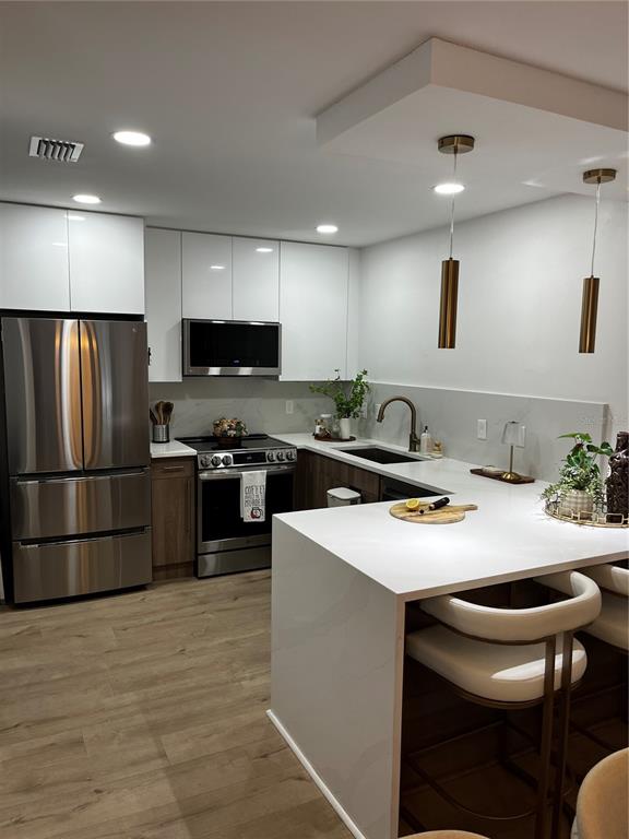 A modern kitchen features white cabinets, stainless steel appliances, and a waterfall-edge island — 110 WINDTREE LANE UNIT 202, WINTER GARDEN, FL